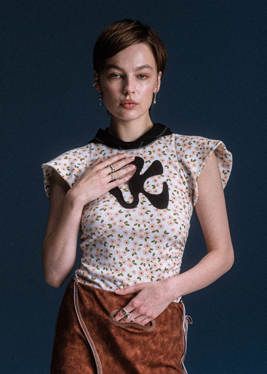 Woman wearing a floral blouse with a black graphic design on a dark background